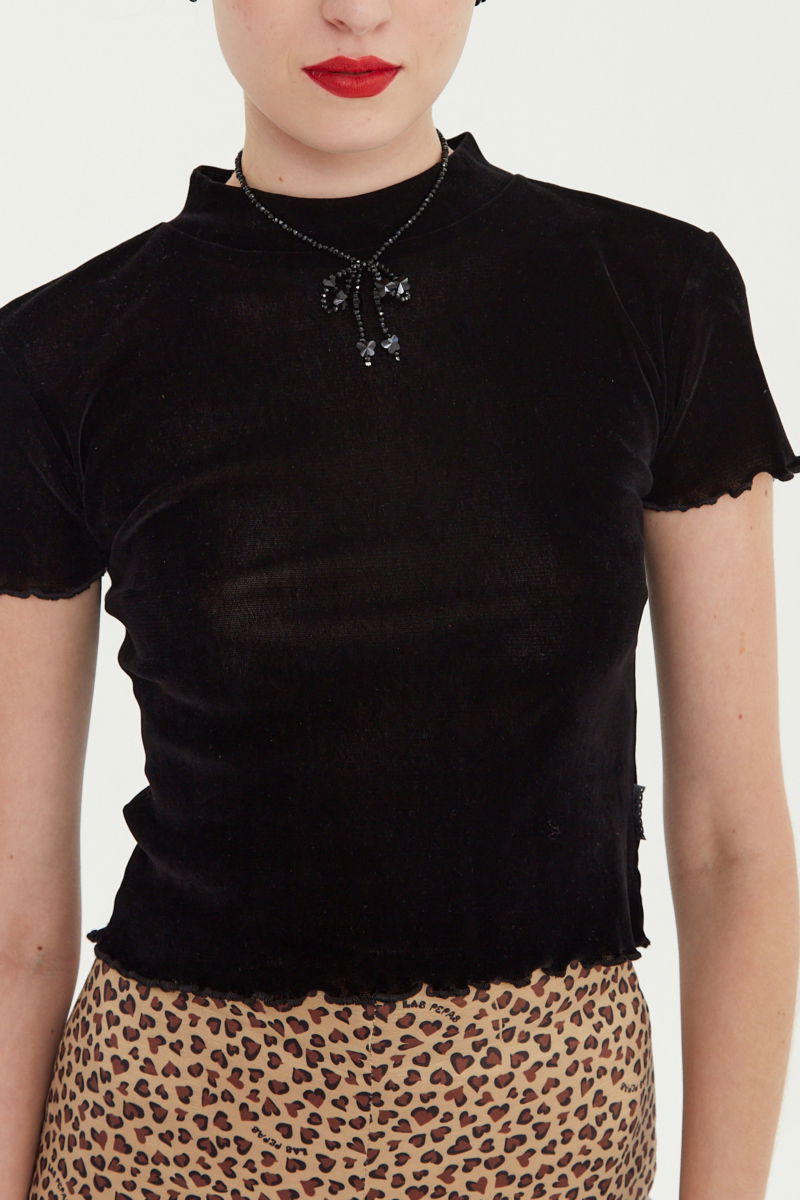 Remera negra al cuerpo de velvet corta a la cintura de mangas cortas y cuello alto con bordado roulotte en mangas y ruedo.