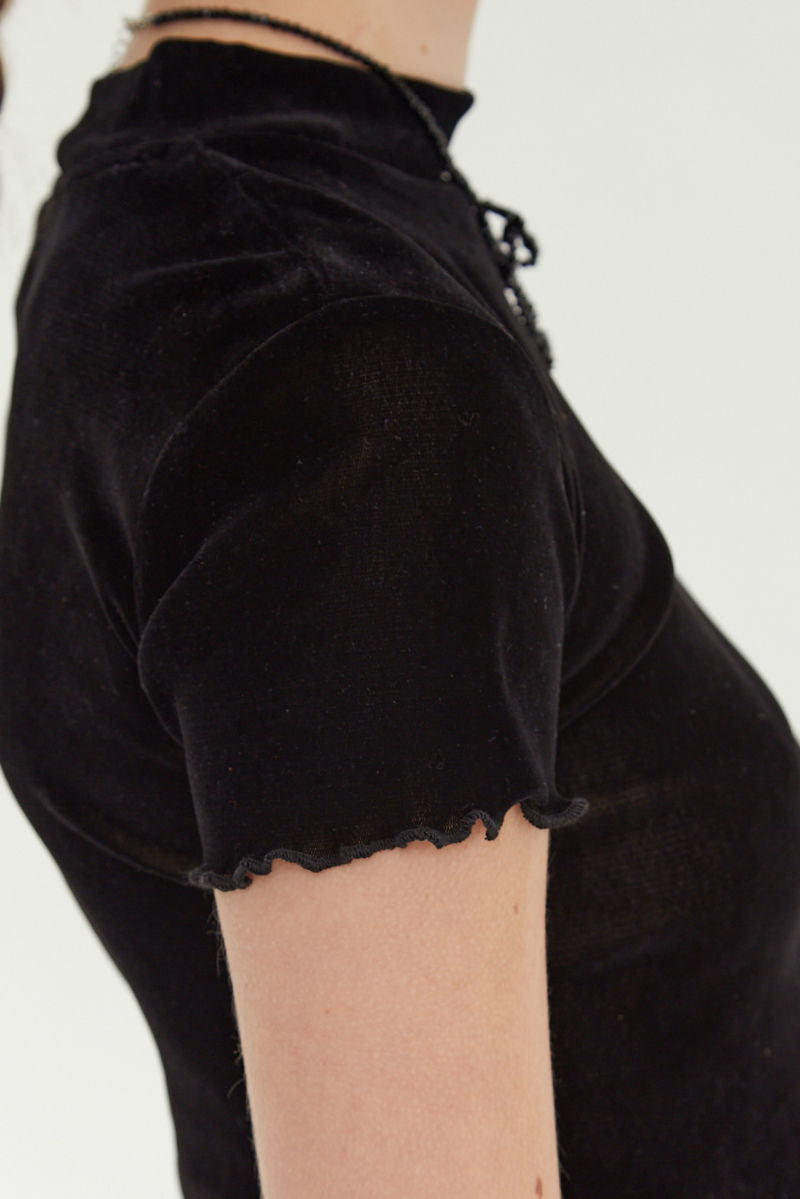 Remera negra al cuerpo de velvet corta a la cintura de mangas cortas y cuello alto con bordado roulotte en mangas y ruedo.