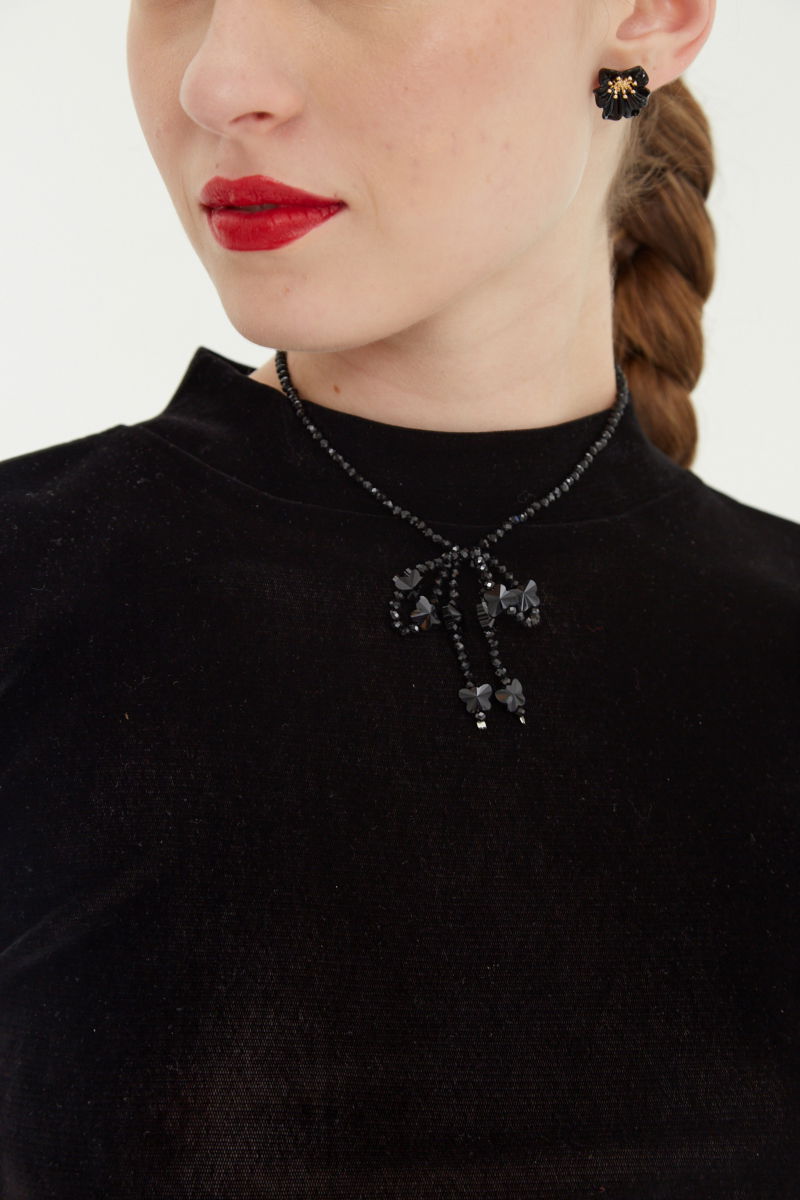 Remera negra al cuerpo de velvet corta a la cintura de mangas cortas y cuello alto con bordado roulotte en mangas y ruedo.