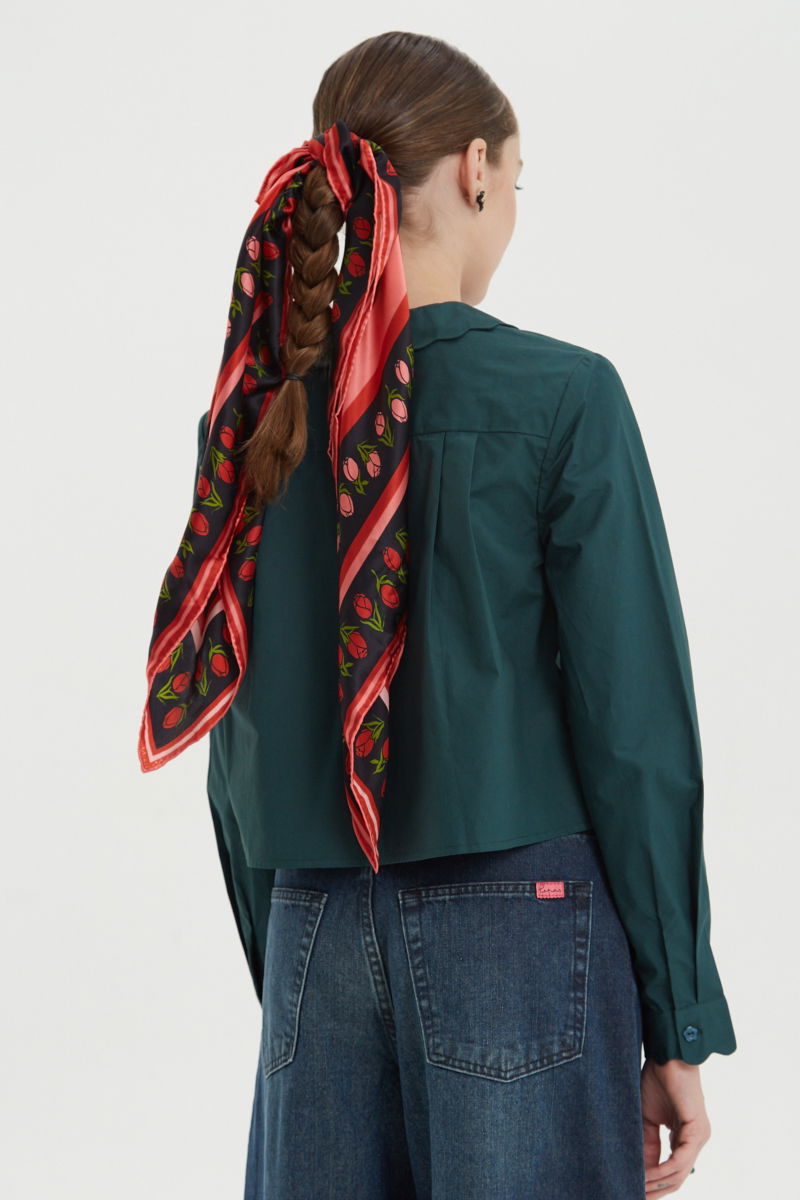 Camisa verde de poplin de largo hasta la cadera con terminación en forma de onditas en cuello, puños y cartera y botones a tono en forma de flor. 