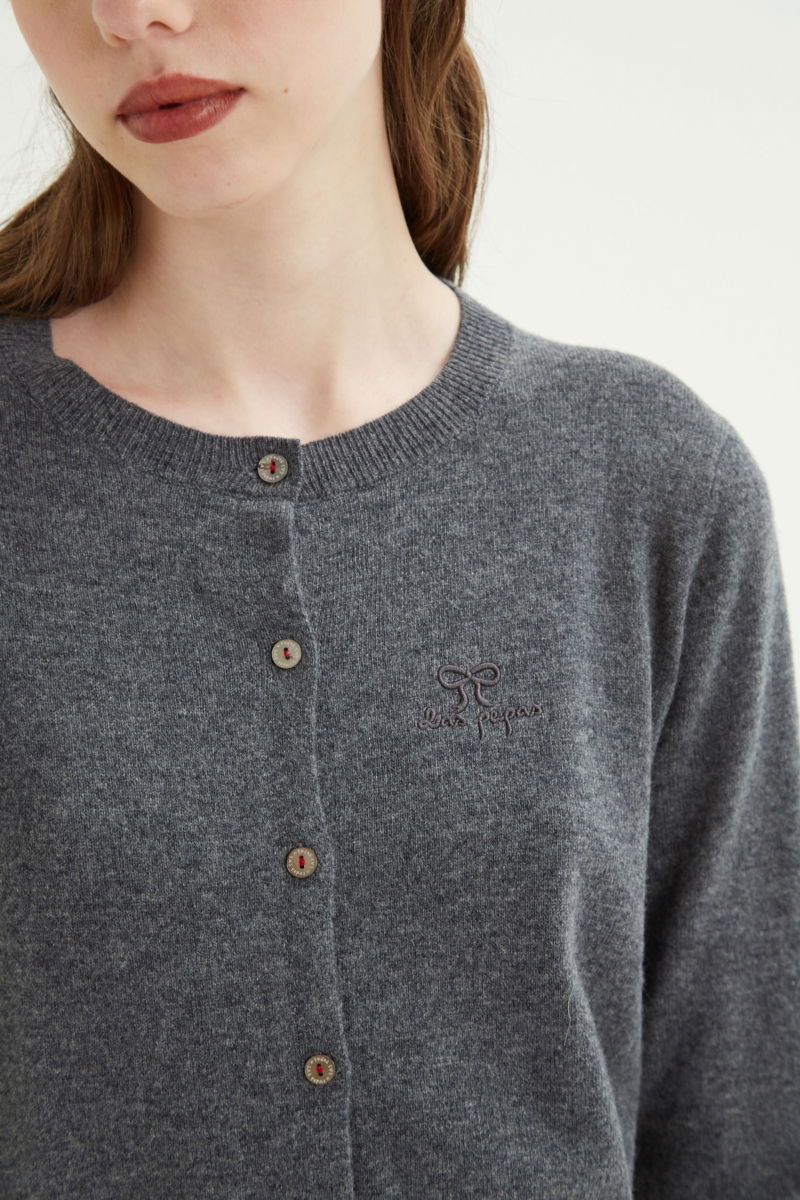 Cardigan gris de lana y cachemira de corte recto entallado en la cintura con terminaciones en rib en puños y ruedo, cuello redondo cerrado y botones a tono.