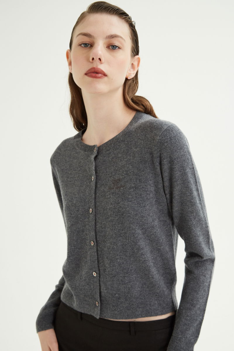 Cardigan gris de lana y cachemira de corte recto entallado en la cintura con terminaciones en rib en puños y ruedo, cuello redondo cerrado y botones a tono.