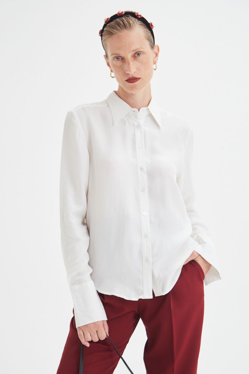 Camisa blanca de calce recto y puños anchos con textura suave de piel de durazno. 
