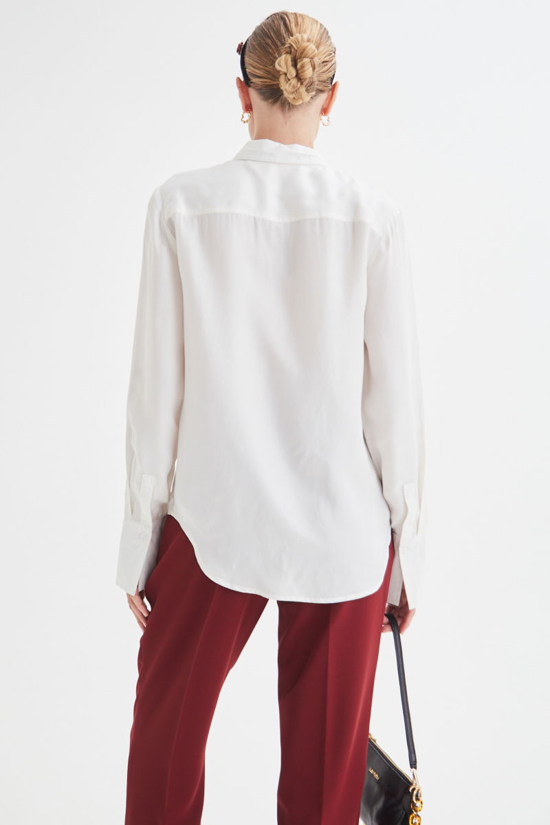 Camisa blanca de calce recto y puños anchos con textura suave de piel de durazno. 
