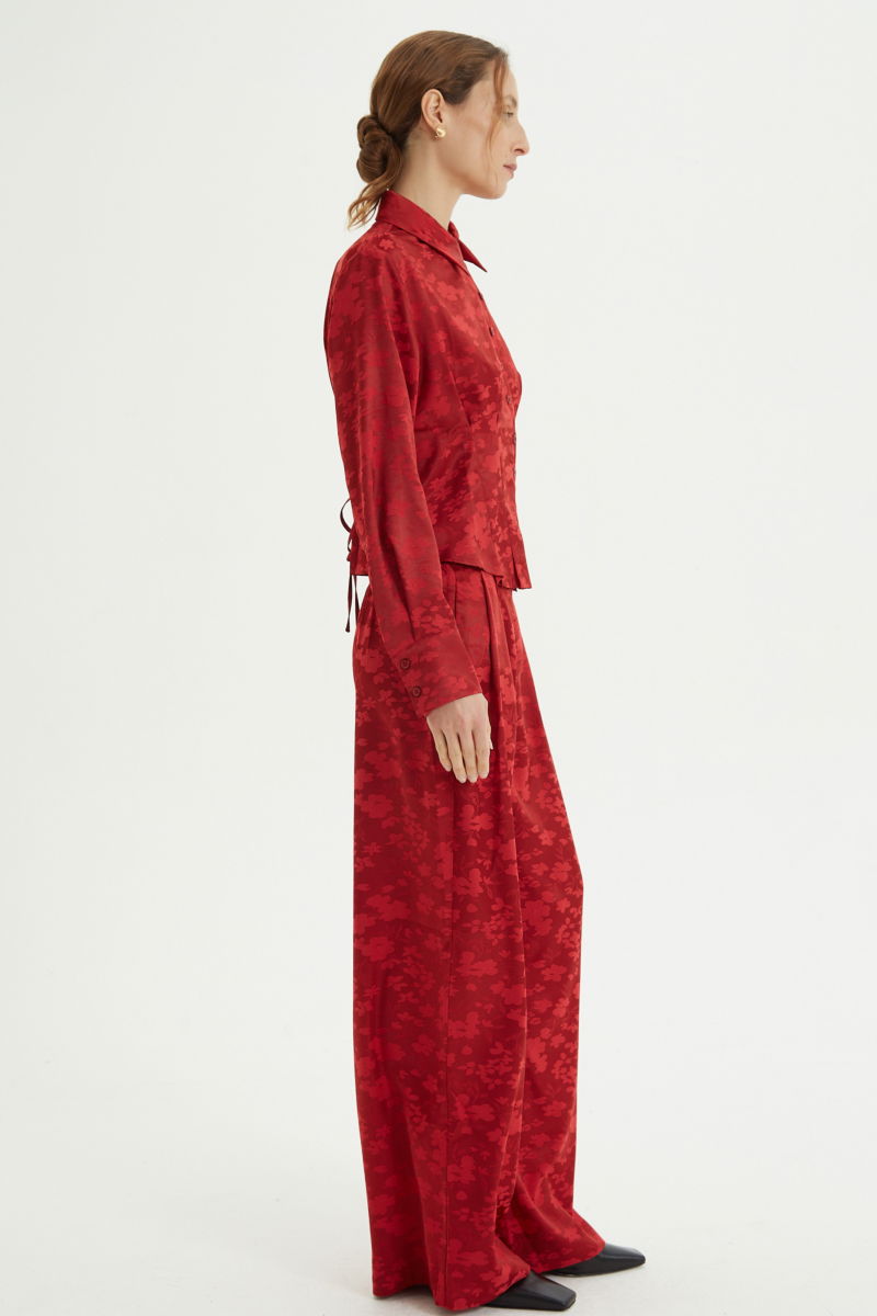 Camisa roja satinada de jacquard floreado con pinzas de entalle en frente y espalda, con lazo para regular. 