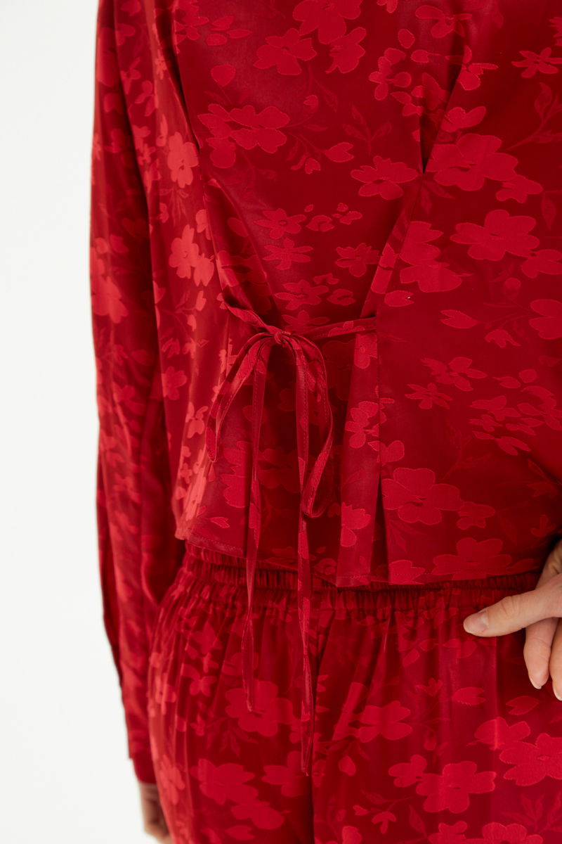 Camisa roja satinada de jacquard floreado con pinzas de entalle en frente y espalda, con lazo para regular. 