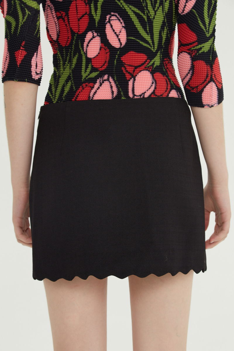 Mini falda negro sastrera tiro medio de silueta recta con terminación ondulada en el ruedo. 
