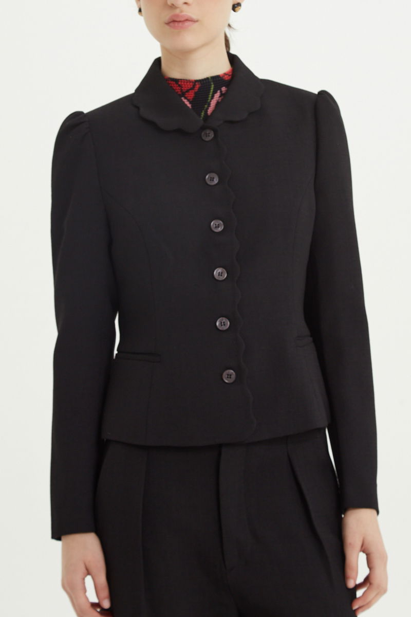 Blazer negro sastrero entallado con terminación ondulada y mangas princesa. 
