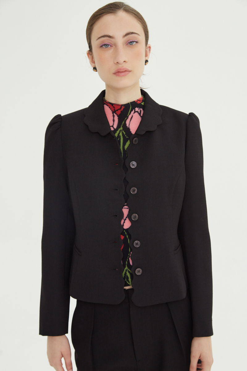 Blazer negro sastrero entallado con terminación ondulada y mangas princesa. 
