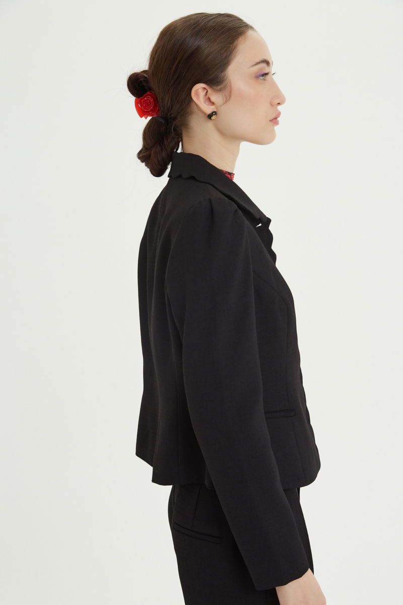 Blazer negro sastrero entallado con terminación ondulada y mangas princesa. 
