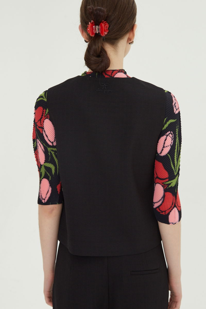 Chaleco negro sastrero con terminación ondulada y botones a tono. 
