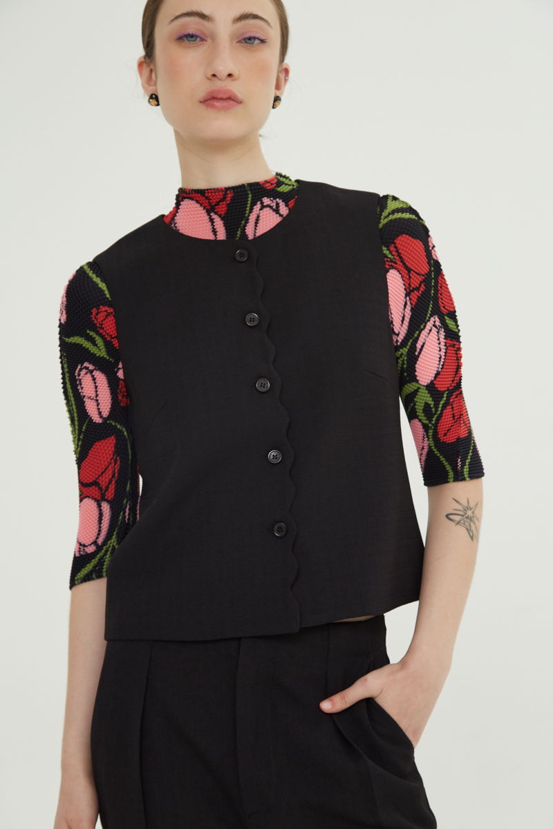 Chaleco negro sastrero con terminación ondulada y botones a tono. 
