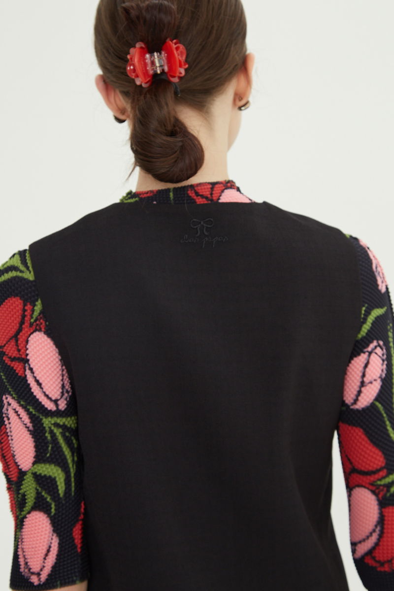 Chaleco negro sastrero con terminación ondulada y botones a tono. 
