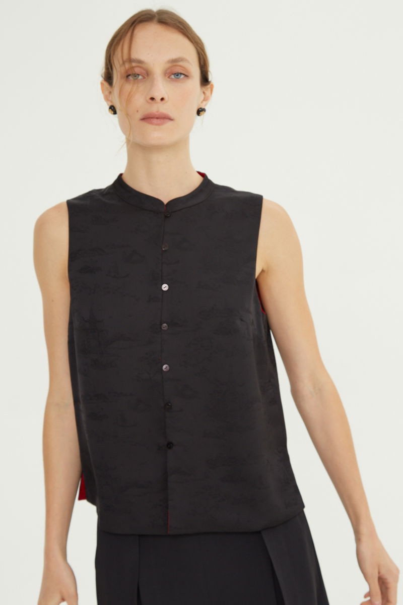 Blusa negra reversible de jacquard satinado sin mangas con cuello mao, botones a tono, pinzas frontales y aberturas laterales.