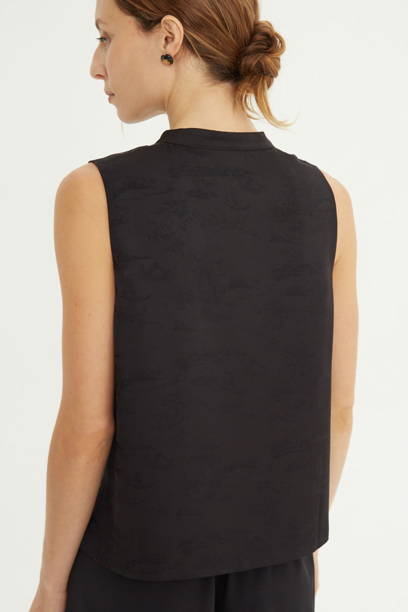 Blusa negra reversible de jacquard satinado sin mangas con cuello mao, botones a tono, pinzas frontales y aberturas laterales.