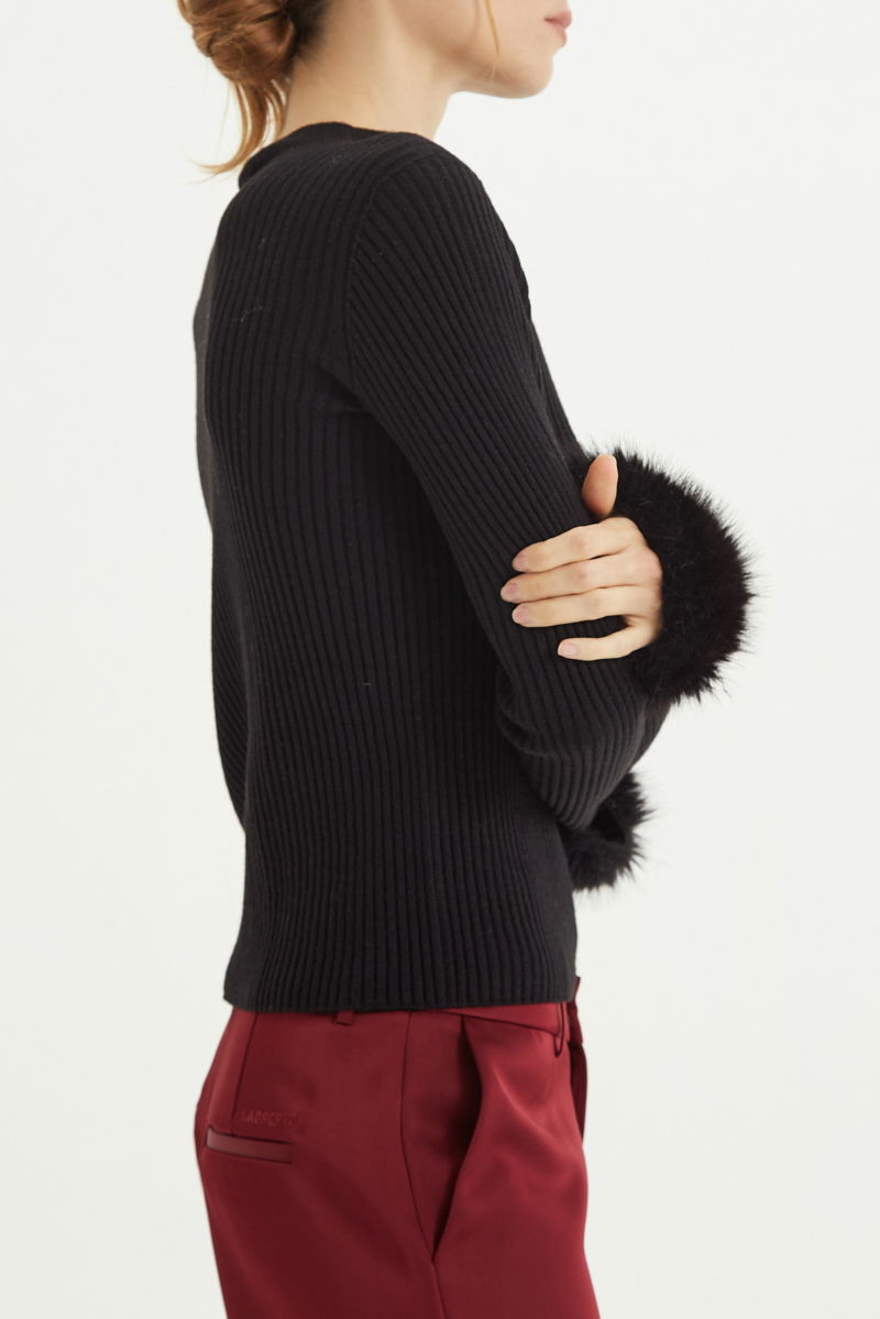 Sweater negro de morley al cuerpo con cuello redondo y puños de pelo. 