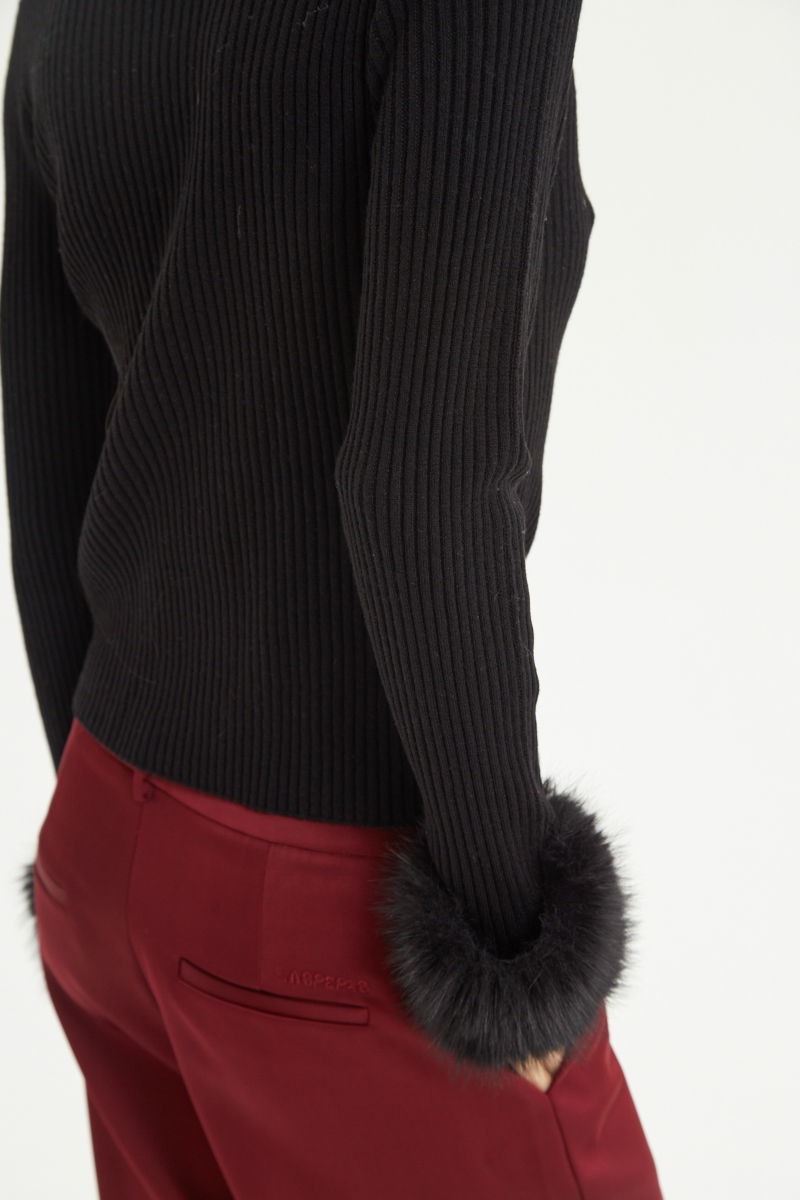 Sweater negro de morley al cuerpo con cuello redondo y puños de pelo. 