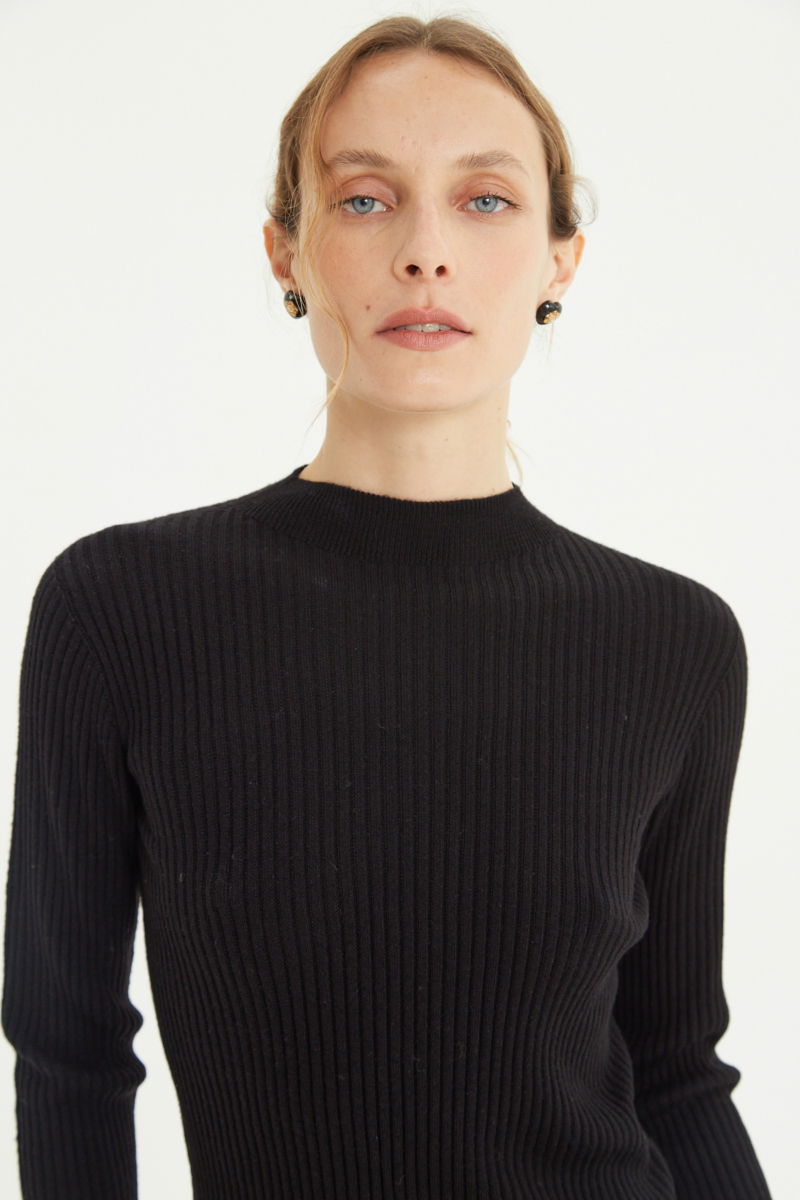 Sweater negro de morley al cuerpo con cuello redondo y puños de pelo. 