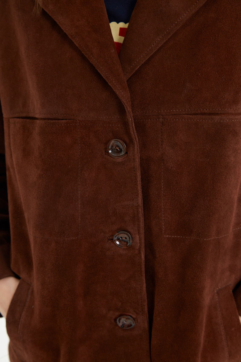 Saco oversize de gamuza largo debajo de la cadera con botones nacarados, bolsillos frontales y laterales y recortes. 
