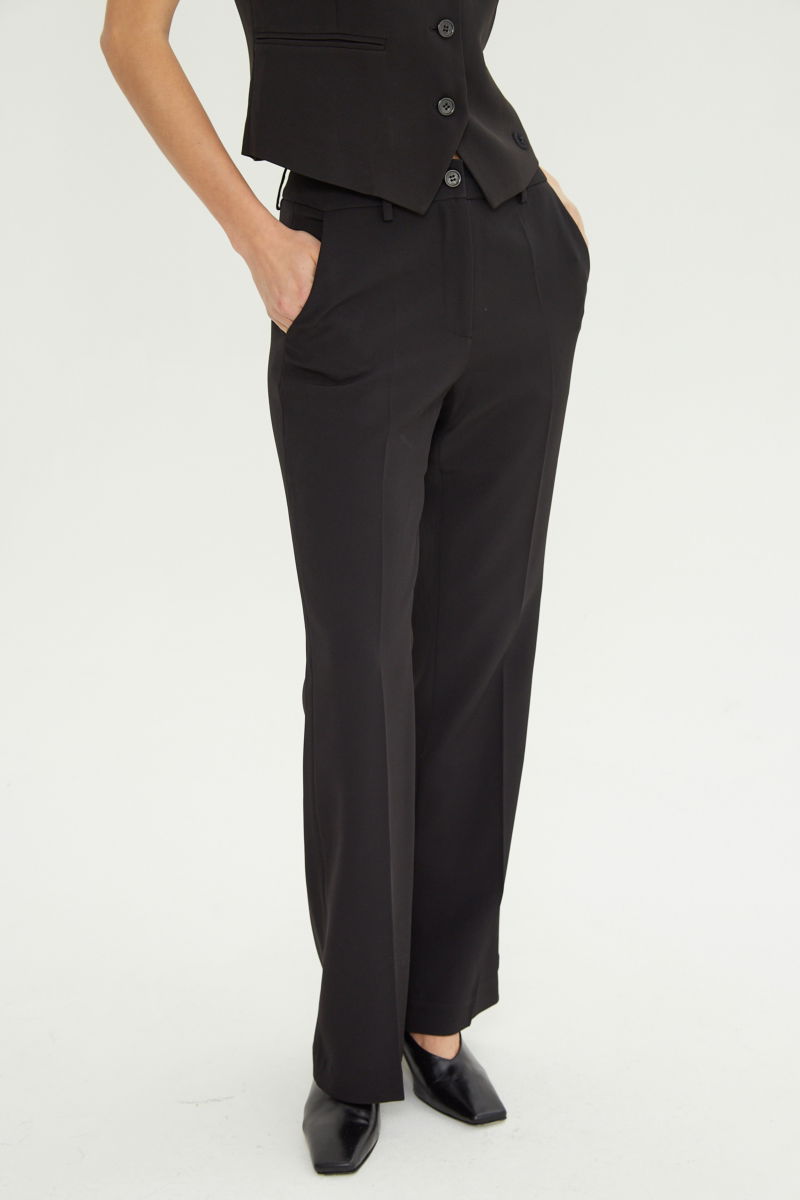 Pantalón negro sastrero tiro alto de corte recto y largo al tobillo con pinzas en el frente, bolsillos laterales y bolsillo ojal en la espalda. 
