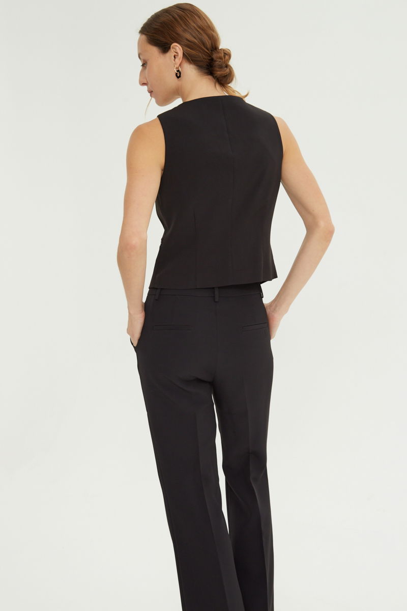 Chaleco negro sastrero largo a la cadera con botones a tono, bolsillos ojal y pinzas en frente y espalda. 
