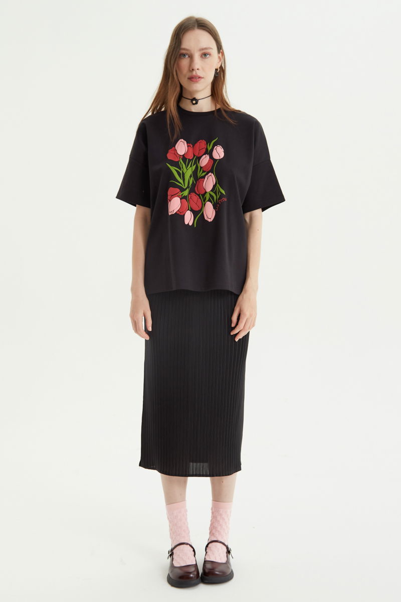 Falda negra midi plisada satinada con elástico en la cintura. Su fit es entallado, se estira y se adapta al cuerpo, con tajos laterales en el ruedo