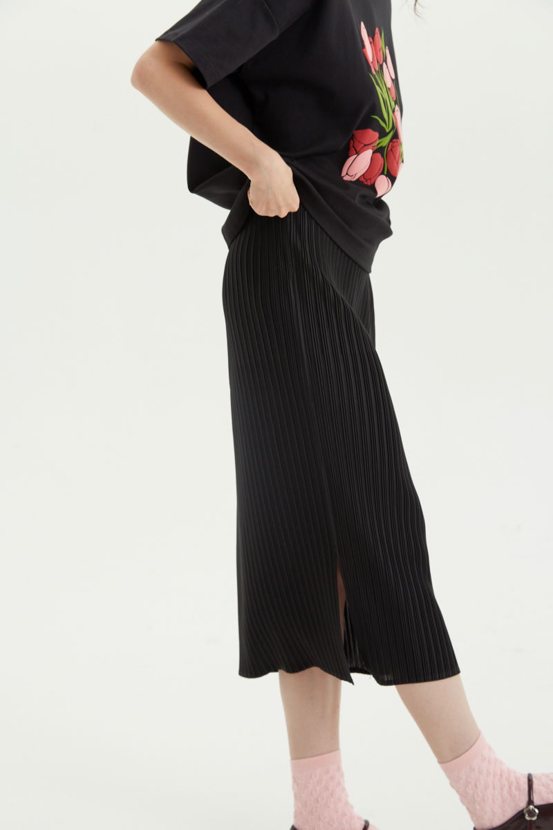 Falda negra midi plisada satinada con elástico en la cintura. Su fit es entallado, se estira y se adapta al cuerpo, con tajos laterales en el ruedo