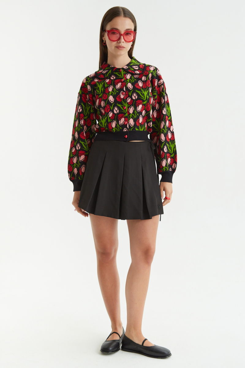 Falda negra sastrera acampanada con sobre falda tableada con lazo para atar en el lateral. 