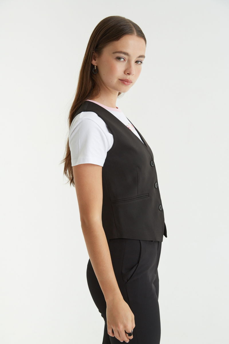 Chaleco negro sastrero largo a la cadera con botones a tono, bolsillos ojal y pinzas en frente y espalda. 
