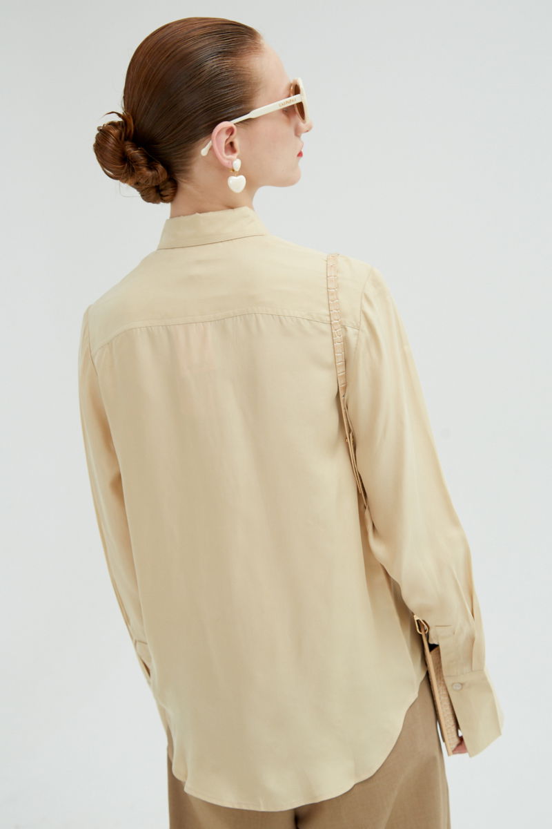 Camisa beige de calce recto y puños anchos con textura suave de piel de durazno. 
