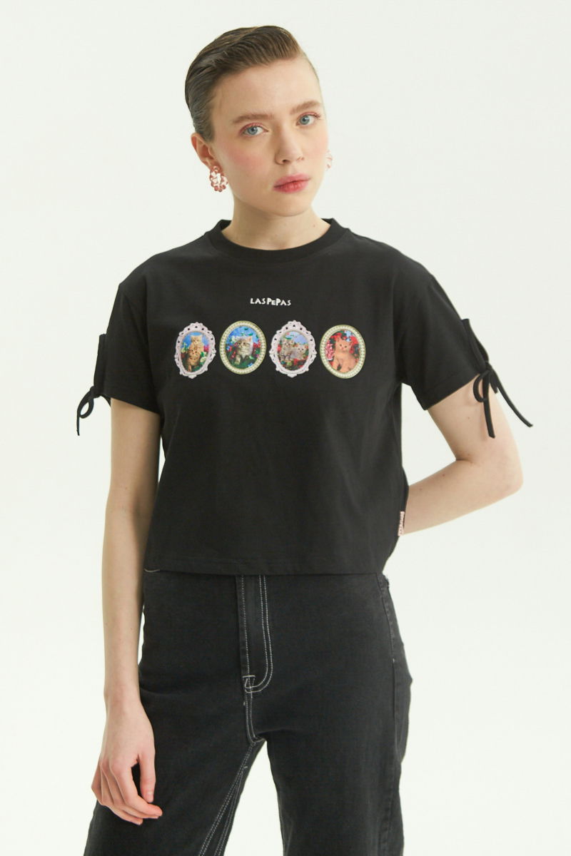 Remera negra suelta y crop de algodón estampada con lazos en las mangas para atar en moño.
