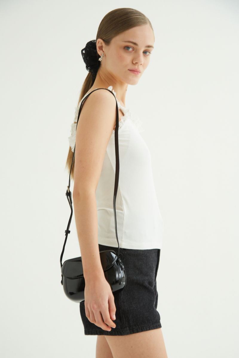 Musculosa negra de morley con breteles finos y cuello con volados de encaje.
