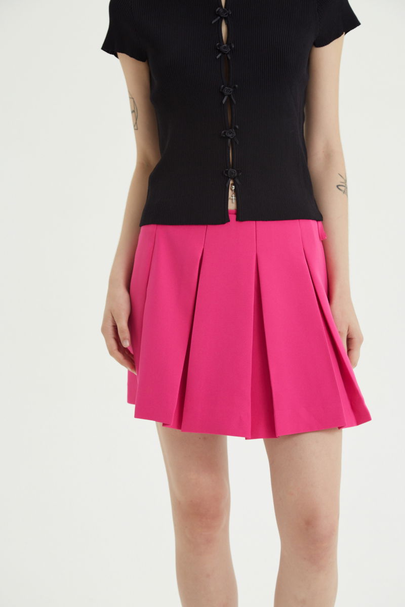 Falda fucsia sastrera acampanada con sobre falda tableada con lazo para atar en el lateral. 