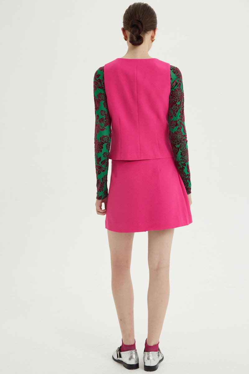 Falda fucsia sastrera acampanada con sobre falda tableada con lazo para atar en el lateral. 