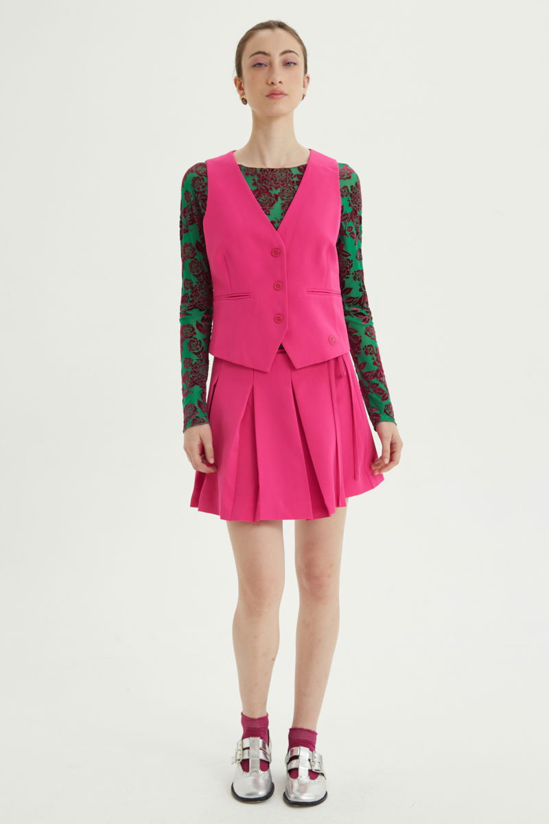 Falda fucsia sastrera acampanada con sobre falda tableada con lazo para atar en el lateral. 