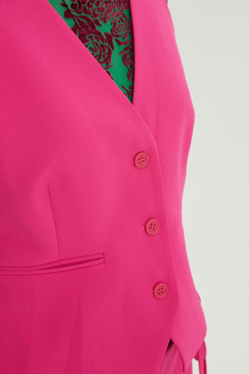 Chaleco fucsia sastrero largo a la cadera con botones a tono, bolsillos ojal y pinzas en frente y espalda. 
