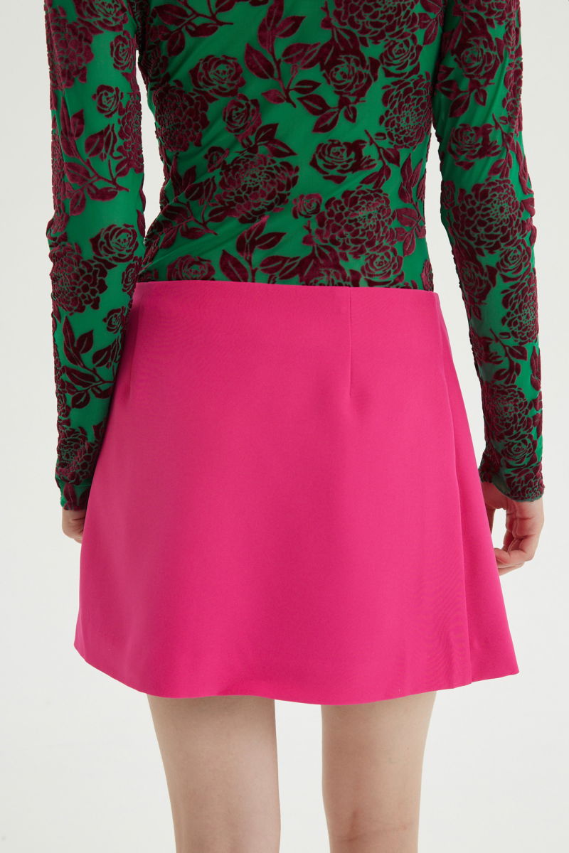 Falda fucsia sastrera acampanada con sobre falda tableada con lazo para atar en el lateral. 