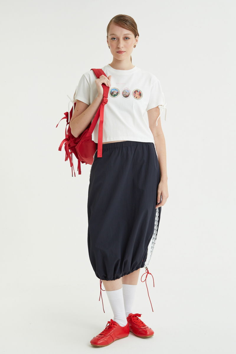 Remera blanca suelta y crop de algodón estampada con lazos en las mangas para atar en moño.
