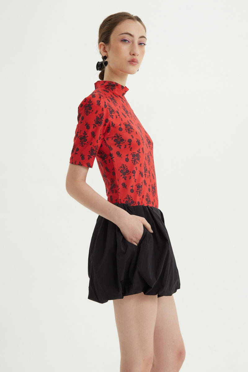 Remera roja entallada y larga a la cadera con cuello semi polera y mangas ¾ con frunces, estampada con print de rosas. 