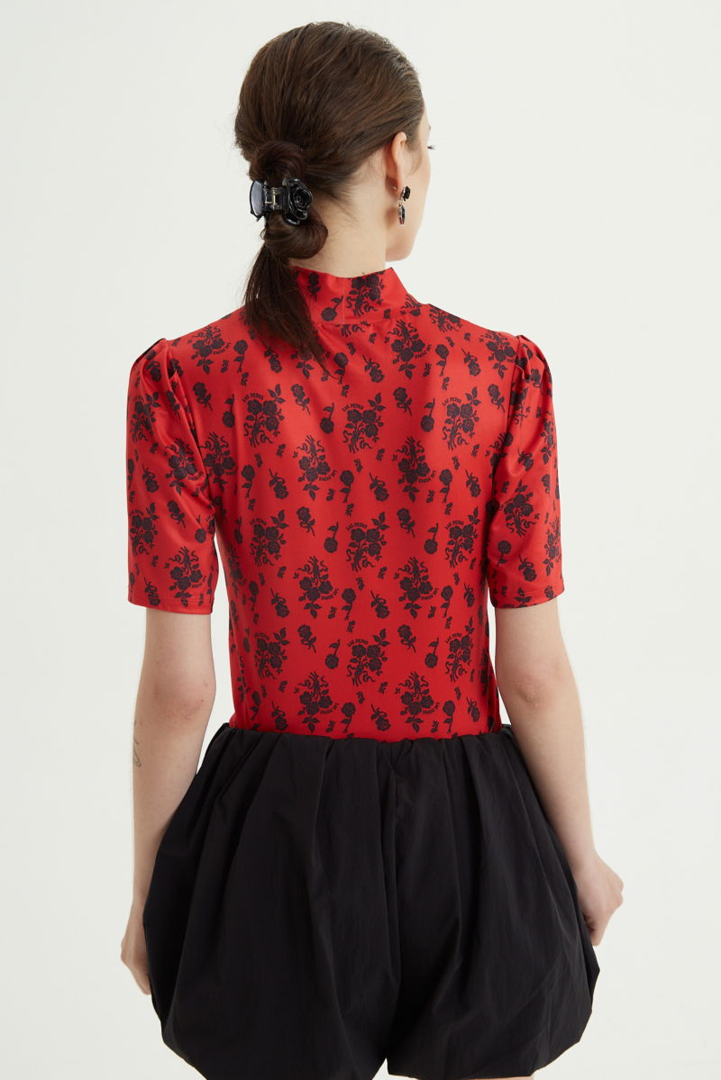Remera roja entallada y larga a la cadera con cuello semi polera y mangas ¾ con frunces, estampada con print de rosas. 