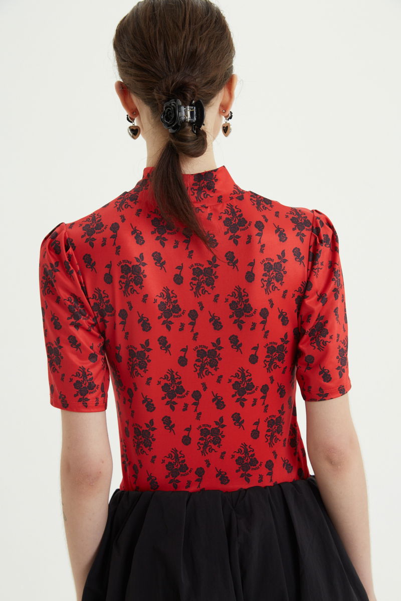 Remera roja entallada y larga a la cadera con cuello semi polera y mangas ¾ con frunces, estampada con print de rosas. 