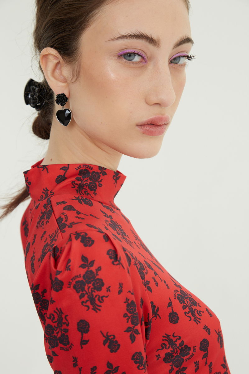 Remera roja entallada y larga a la cadera con cuello semi polera y mangas ¾ con frunces, estampada con print de rosas. 