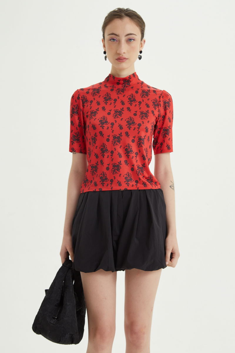 Remera roja entallada y larga a la cadera con cuello semi polera y mangas ¾ con frunces, estampada con print de rosas. 