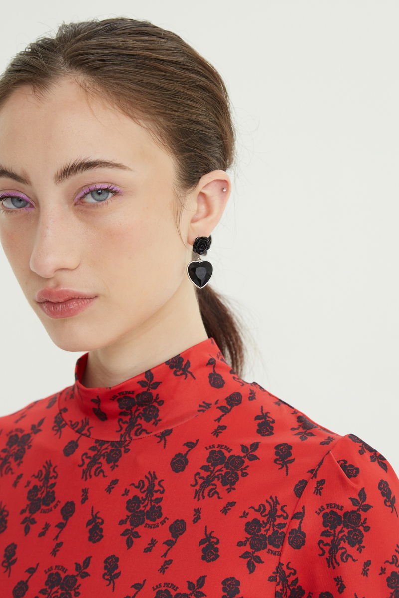 Remera roja entallada y larga a la cadera con cuello semi polera y mangas ¾ con frunces, estampada con print de rosas. 