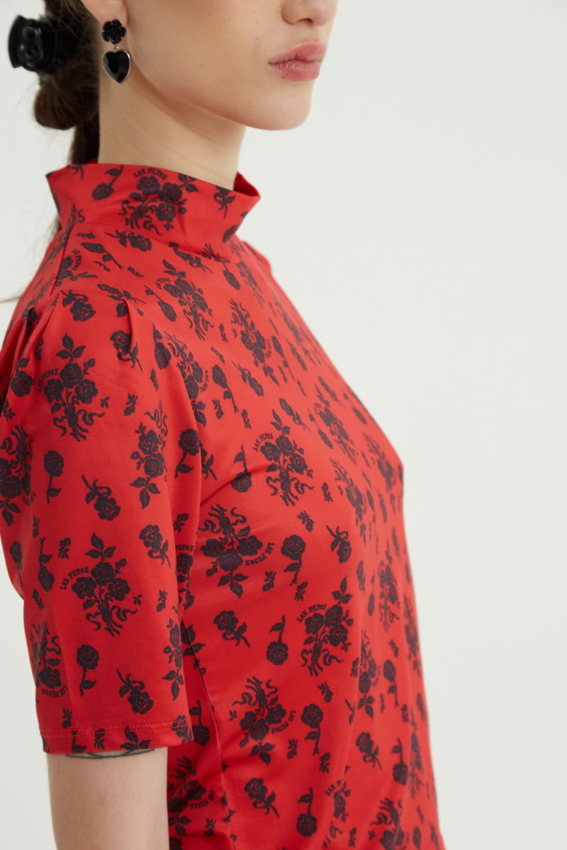 Remera roja entallada y larga a la cadera con cuello semi polera y mangas ¾ con frunces, estampada con print de rosas. 
