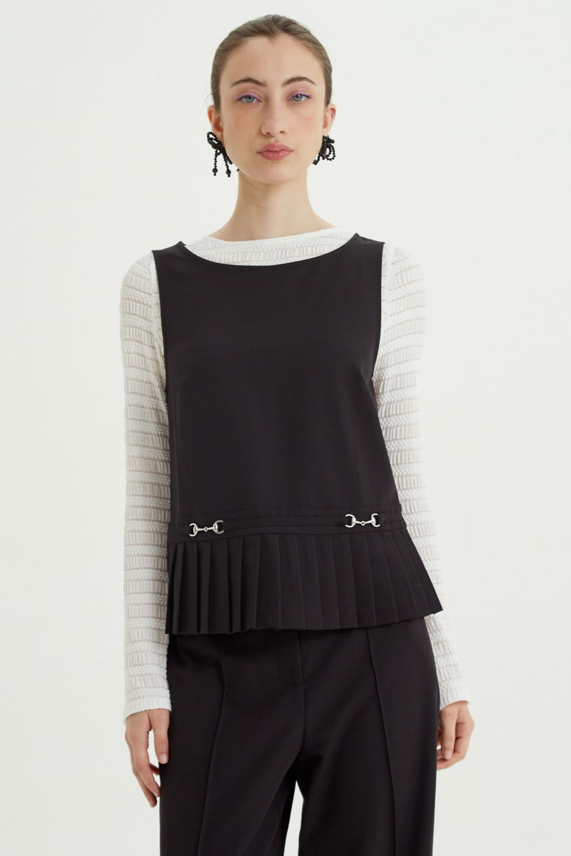 Blusa negra sastrera sin mangas con tablas en la cintura, herrajes metálicos y escote a la base del cuello, larga a la cadera. 