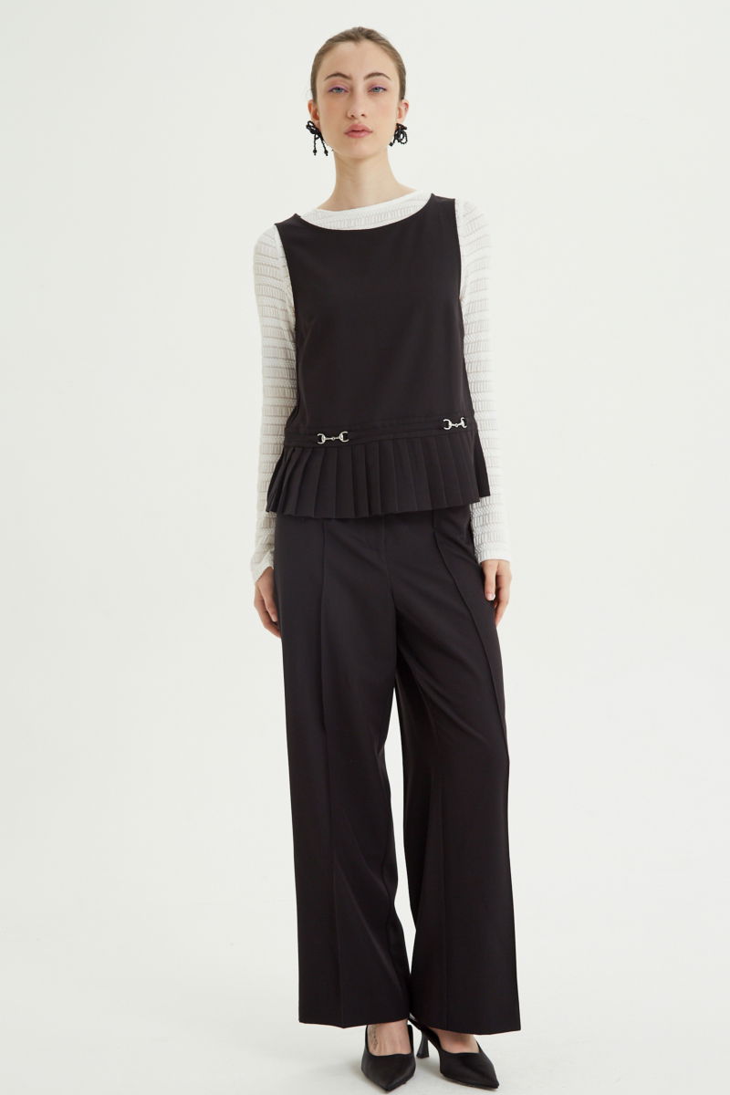 Pantalón negro sastrero tiro alto y recto con herrajes metálicos, pliegue en las piernas y elástico en la cintura trasera. 
