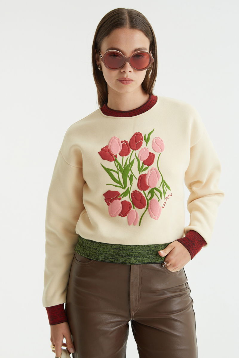 Buzo con estampa de tulipanes en relieve, recto y largo a la cadera con hombros caídos y terminaciones de rib jaspeado a contratono en cuello, puños y ruedo.