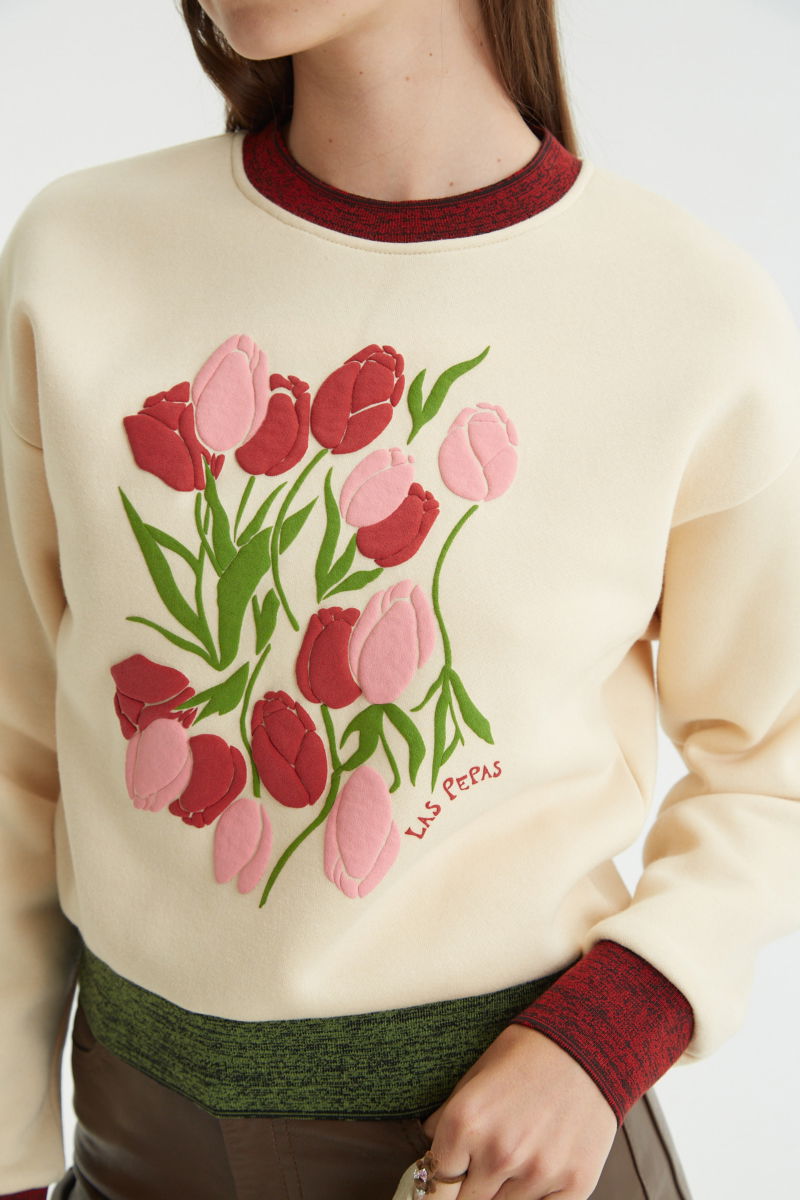 Buzo con estampa de tulipanes en relieve, recto y largo a la cadera con hombros caídos y terminaciones de rib jaspeado a contratono en cuello, puños y ruedo.