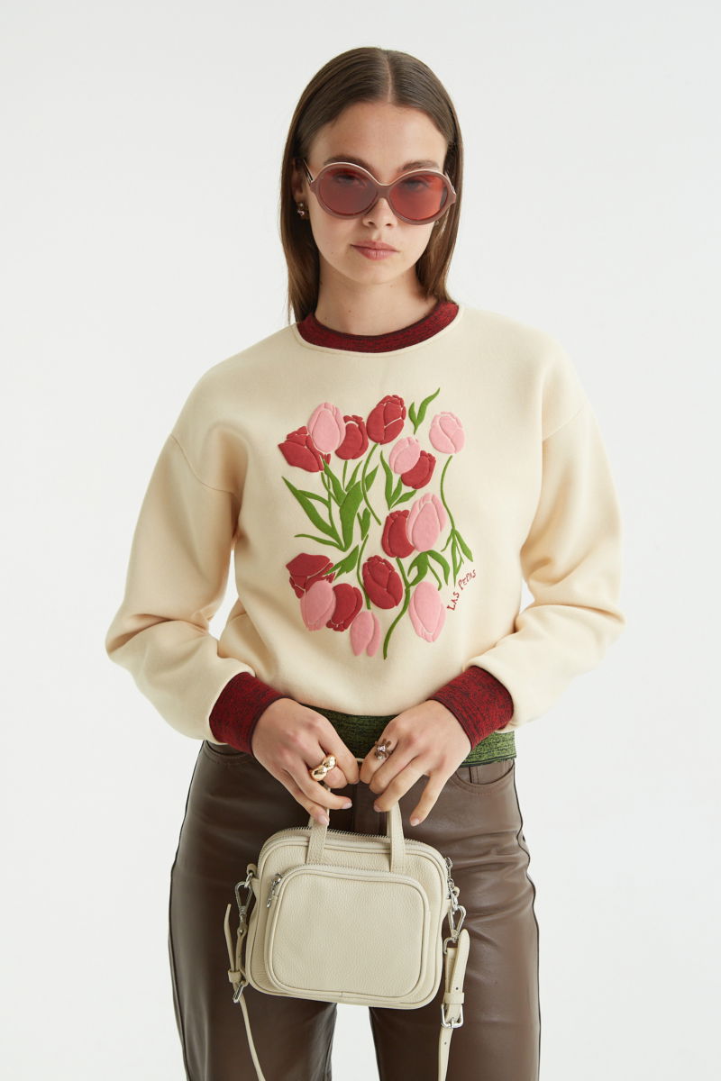 Buzo con estampa de tulipanes en relieve, recto y largo a la cadera con hombros caídos y terminaciones de rib jaspeado a contratono en cuello, puños y ruedo.